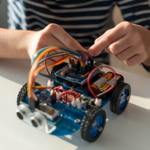 un enfant participe à un stage de vacances de robotique et monte un robot puis le programme sous Scratch, C ou Python