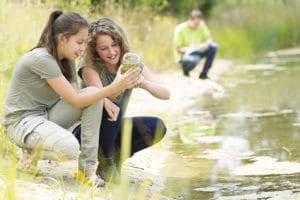 des adolescentes étudient la faune le long d'un cours d'eau