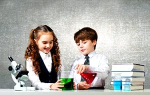 un garçon et une fille réalisent ensemble des experiences scientifiques dans le cadre d'un établissement scolaire