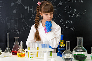 Une jeune fille observe des fioles de chimie dans le cadre d'expériences scientifiques menées dans le stage de vacances pour enfants à Aix-en-Provence.