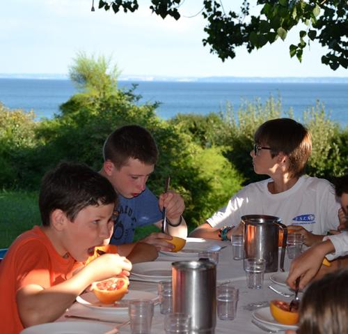 des enfants prennent leur petit déjeuner face à la mer dans un centre de séjour et colonies de vacances