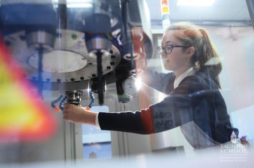 Une adolescente participant au séjour linguistique en Angleterre fabrique son projet scientifique STEM et manipule une fraiseuse au sein du FabLab de l'internat.